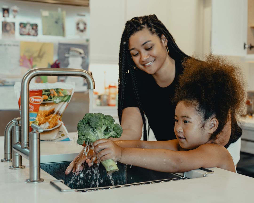 mom-teaching-daughter-to-wash-vegetables-by-tyson-at-unsplash