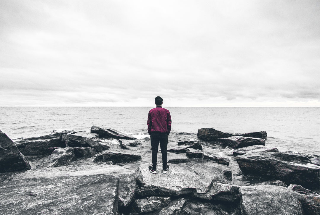 man-standing-on-the-rocks-watching-the-sea-by-warren-8iwdsT-unplash